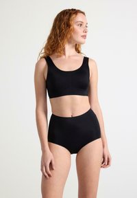 Mustat bralette, jossa on leveät hihnat, sekä korkeavyötäröiset mustat alushousut, jotka on valmistettu sileästä kankaasta, saumattomalla muotoilulla ja minimalistisella tyylillä.