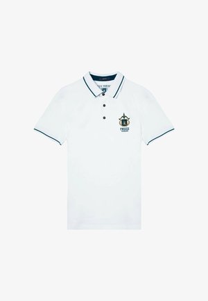 Polo shirt bianco con una patta di bottoni, dettagli neri sul colletto e sulle maniche, con un emblema ricamato sul lato sinistro del petto.