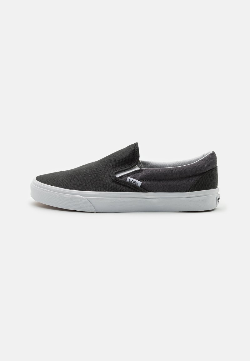 Černé plátěné slip-on boty s gumovou podrážkou, které mají nízkoprofilový design a elastické boční detaily pro snadné obouvání.