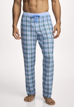 Man wearing light blue and green plaid pajama pants with a blue drawstring, standing barefoot against a plain background.