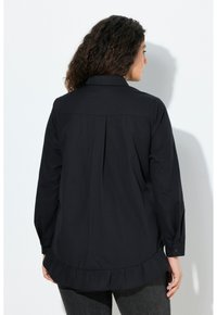 Black button-up shirt featuring a ruffled hem, long sleeves, a back pleat detail, and a classic collar. Made from smooth fabric.