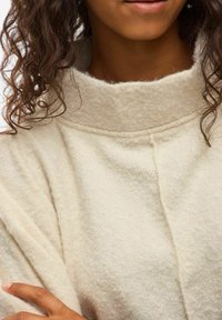 Off-white, tekstureret sweater med høj krave. Har en sømdetail langs forsiden og blødt, hyggeligt stof. Pænt draperet lag nær skulderen.