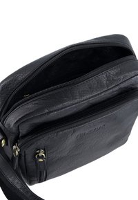 Černá kožená kabelka přes rameno se dvěma zipovými přihrádkami, texturovaným povrchem a nastavitelným popruhem. Má zlaté kovové doplňky.