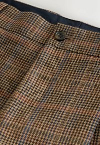 Brown plaid trousers with a checkered pattern, featuring blue and red accents, a button closure, and a textured fabric.