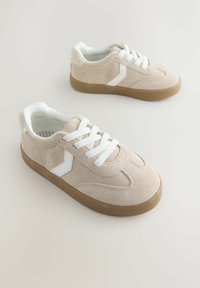 Beige suede sneakers with white laces and a textured rubber sole. Features a white accent design and a soft interior lining.