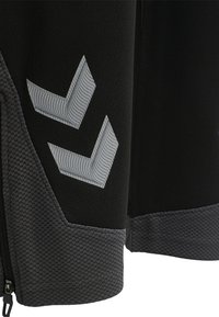 Schwarze Sportjacke mit grauen strukturierten Akzenten, mit einem Zickzack-Logo auf dem oberen Ärmel und einem strukturierten Saum.