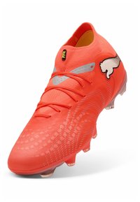 Kirkkaan oranssi Puma-jalkapallokenkä, jossa nauhat, teksturoitu päällinen, hopeiset yksityiskohdat ja kirkas nastallinen pohja, kuvattu sivulta ja edestä vinottain.