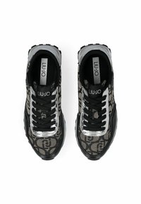 Black and beige sneakers featuring a logo-patterned fabric upper, metallic silver accents, and a thick black rubber sole.