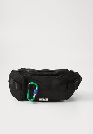 Sort nylon taljebælte med lynlås, justerbar rem og en grøn og blå karabiner fastgjort foran.