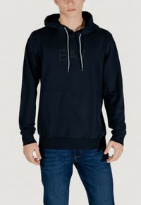 Hoodie bleu marine avec une poche avant, capuche avec cordon de serrage et logo embossé. Fabriqué en un doux mélange de coton, il possède des poignets et un ourlet côtelés.