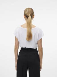 Cămașă albă cu mânecă scurtă, cu un croi lejer, asortată cu pantaloni negri cu talie înaltă, cu o textură netedă și detalii cu nasturi pe spate.