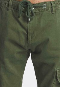 Olijfgroene cargoshorts van katoen, met een trekkoordsluiting, versterkte stiksels en zijzakken. Soepele textuur met een matte afwerking.
