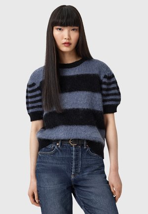 Maglione lavorato a maglia con strisce nere e blu, maniche puff corte, scollatura rotonda, tessuto morbido. Abbinato a jeans in denim blu e una cintura nera.