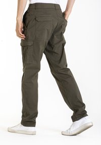 Pantalons cargo en tissu vert olive, dotés de plusieurs poches, d'une coupe décontractée et de jambes fuselées, associés à des baskets blanches.