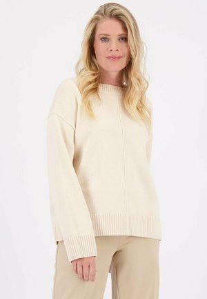 Beige gebreide trui met een geribde onderrand en manchetjes, met een ronde halslijn en een ontspannen pasvorm. Gladde textuur en minimalistisch ontwerp.