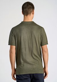 Kortsleeve, olivgrön polo med en strukturerad väv, ribbad krage och manschetter, med rak fåll och sidofickor.