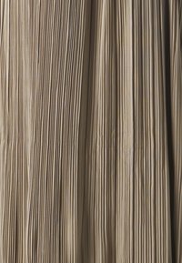 Fållad tyg med vertikala, jämnt fördelade veck i mjuka beige nyanser, som visar en slät textur och ett enhetligt mönster.