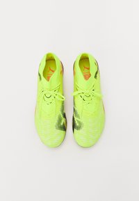 Chaussures de football néon jaunes avec une tige texturée, des accents noirs et orange, et un motif rayé contrasté. Comprend des lacets et une conception ajustée.