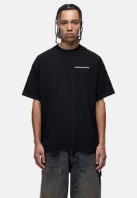 Zwarte katoen T-shirt met een losse pasvorm, ronde halslijn en korte mouwen. Bevat witte tekst "GOODFOR NOTHING" op de borst.