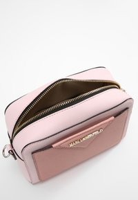 Borsa a mano rettangolare rosa con finitura testurizzata, zip dorata e dettagli neri. Presenta una tasca frontale curvata con dettagli del logo.