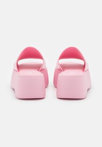 Infradito in schiuma rosa con un ampio cinturino e una suola rialzata e spessa. Texture liscia con un finish opaco. Design semplice e moderno.