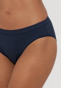 Granatowe bawełniane bikini o gładkiej fakturze, elastycznym pasie i minimalnych detalach szwów. Średni stan oraz pełne pokrycie.