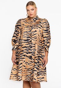 Korte mouw jurk in beige met zwart-wit tijgerstreep patroon, voorzien van een knoopsluiting aan de voorzijde en verzamelde mouwen voor volume.