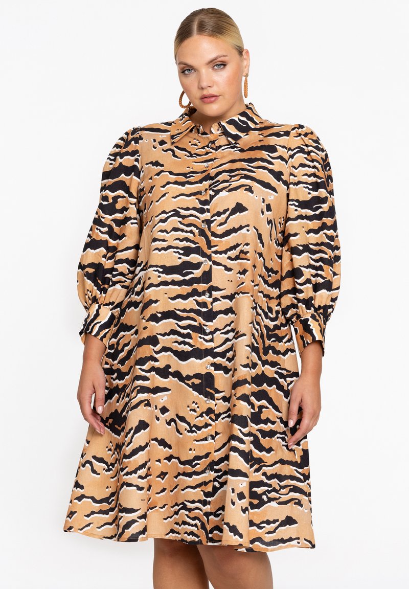 Korte mouw jurk in beige met zwart-wit tijgerstreep patroon, voorzien van een knoopsluiting aan de voorzijde en verzamelde mouwen voor volume.