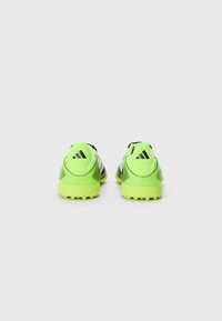 Des chaussures de foot vertes et noires avec un dessus texturé, trois rayures noires et un talon et une semelle contrastés de vert clair.