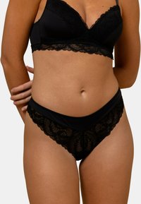 Ensemble de soutien-gorge en dentelle noire et de culotte assortie, présentant des détails en dentelle élaborés, une base en tissu lisse et des bords festonnés le long de la couture.