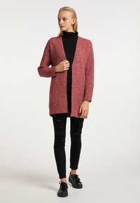 Cardigan texturat, cu deschidere frontală, de culoare burgundy bogat, cu mâneci lungi și croială relaxată, asortat cu blugi negri rupți și adidași.