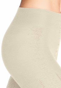 Collants beiges avec une taille côtelée, présentant une texture lisse et des détails décoratifs sur le côté. Matériau transparent avec une légère compression.