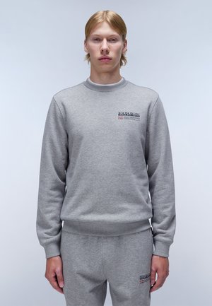 Sudadera gris de material suave, con cuello redondo, puños de canalé y un parche de logo en el lado izquierdo del pecho.