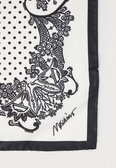 Černobílý hedvábný šátek zdobený puntíky a složitými květinovými vzory podél okrajů, s černým lemem a podpisem designéra.