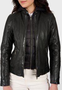 Čierna kožená bunda s predným zipsom, má prešívanú vnútornú vrstvu a kapucňu. Hnedé ramená a zipsové bočné vrecká.