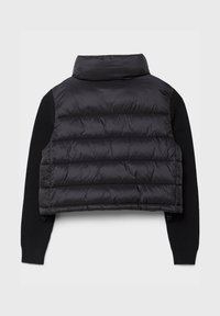 Veste courte en doudoune noire avec un matériau brillant, présentant un col montant et de longues manches tricotées noires. Détails zippés sur les côtés inclus.