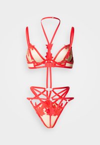 Σετ κόκκινης εσώρουχης με σουτιέν τριγωνικό και τανγκό στο ίδιο ύφος. Κατασκευασμένο από λουράκια με λουλουδένιες διακοσμήσεις και ημιδιάφανο υλικό για αντίθεση.