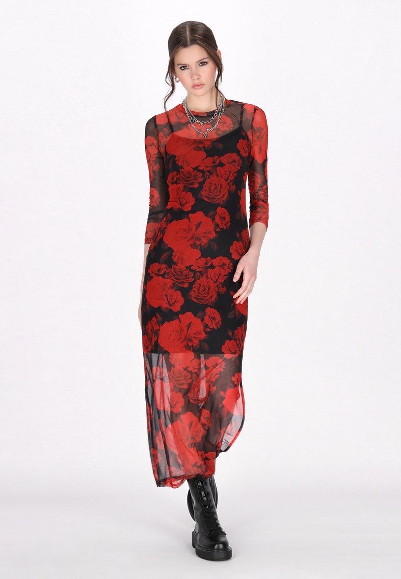 Langes schwarzes Kleid mit rotem Rosenmuster, transparenter Stoff, runder Ausschnitt, lange Ärmel und geschichteter Saum. Getragen mit schwarzen Schnürstiefeln.