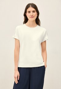 Witte t-shirt met korte mouwen en een ronde halslijn, met gestructureerde schouderdetails, gecombineerd met donkerblauwe wijde broek.