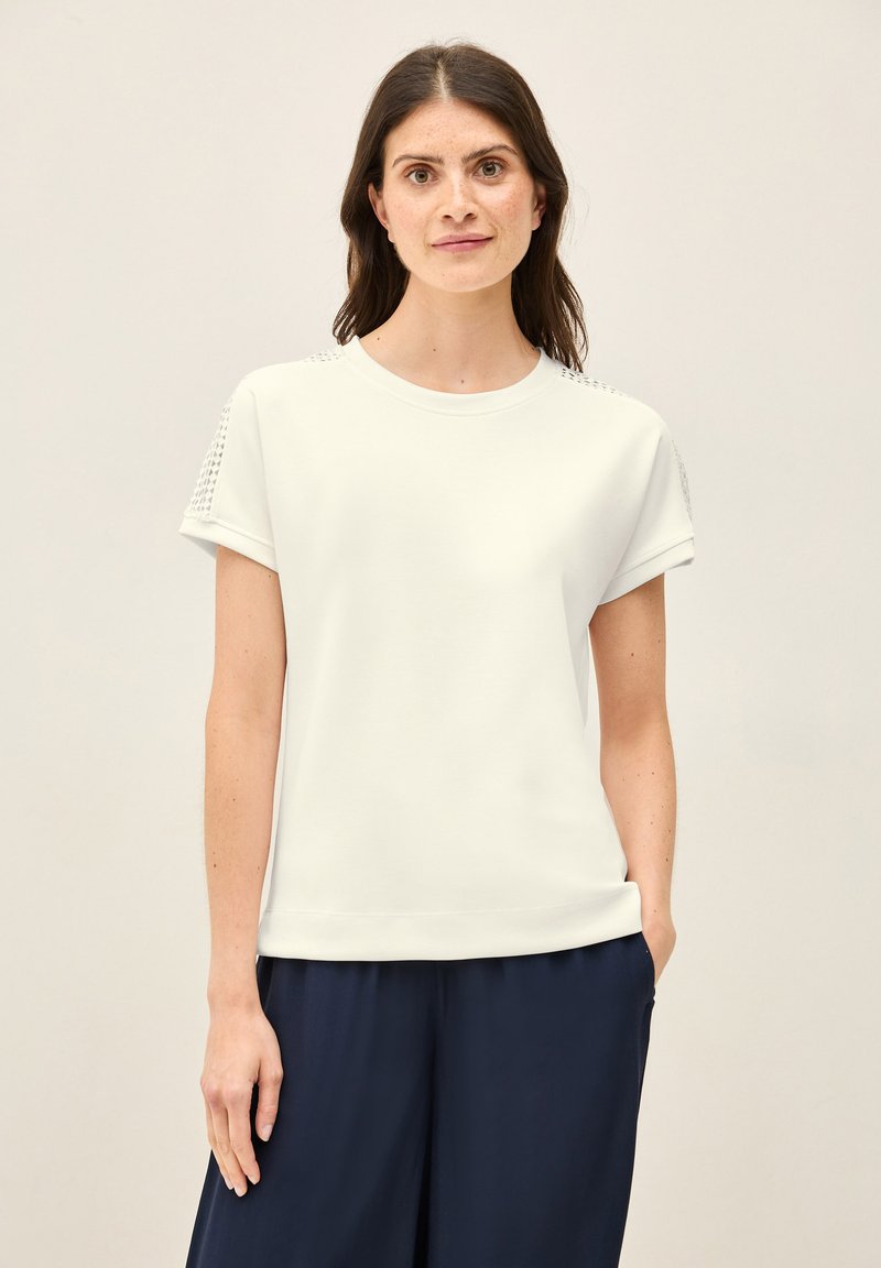 Witte t-shirt met korte mouwen en een ronde halslijn, met gestructureerde schouderdetails, gecombineerd met donkerblauwe wijde broek.