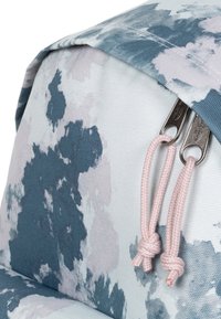 Mochila con estampado floral en tonos azul claro y rosa, que presenta un material suave, cremalleras metálicas dobles y tiradores anudados en rosa.