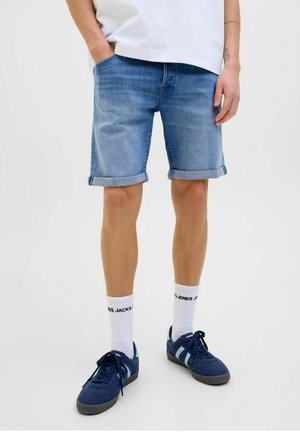 Denim shorts in light blue, featuring rolled hems and side pockets. Paired with navy sneakers and white crew socks with text.