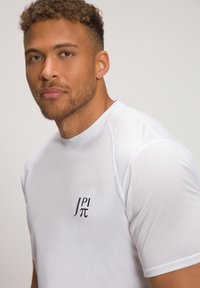 Weißes Sport-T-Shirt mit kurzen Ärmeln, glatter Textur und einem kleinen schwarzen Logo auf der Brust. Mit Mesh-Details an den Schultern.