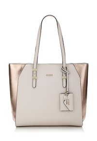 Kangaskassi, jossa on vaaleanbeige etuosa ja metallinhohtoiset rose gold -sivut, kaksinkertaiset olkahihnat ja pieni kiinnitetty tagi avainkoristeella.