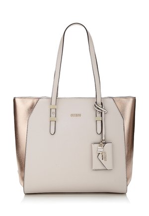 Sac fourre-tout avec un devant beige et des côtés métalliques rose gold, deux poignées épaules, et une petite étiquette attachée avec un charme en forme de clé.