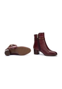 Bottines en cuir bordeaux avec un bout arrondi, une fermeture éclair sur le côté et un talon empilé. Dotées d'une semelle en caoutchouc texturé pour une meilleure adhérence.