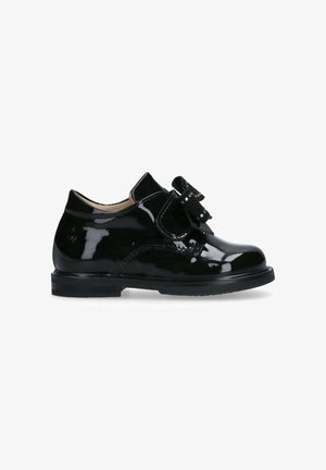 Scarpe in pelle verniciata nera con punta arrotondata, fascia in velcro e un accentuato fiocco decorativo. Suola robusta per una maggiore durata.