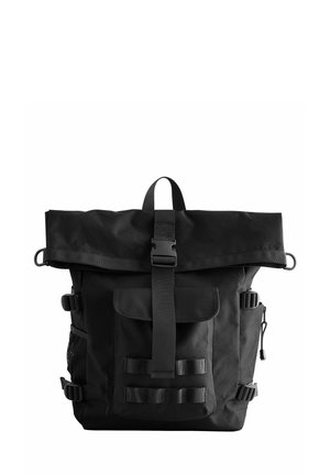 Sac à dos noir à rabat, fabriqué en tissu durable. Il comprend des bretelles réglables, une poche avant, une poche latérale en mesh et une fermeture par boucle.