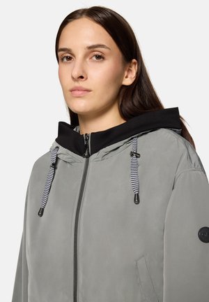 Gray zip-up jacket with a black hood, featuring black drawstrings and a smooth texture. Includes a logo patch on the left sleeve.