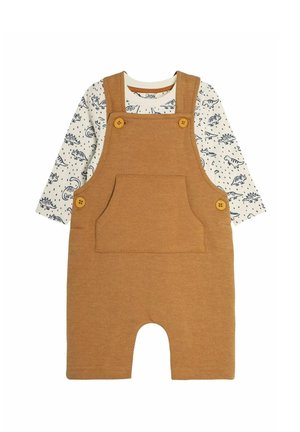 Brune corduroy overalls med justerbare stropper, forlommer og to gule knapper. Underneath en hvid langærmet skjorte med blåt dinosaurprint.